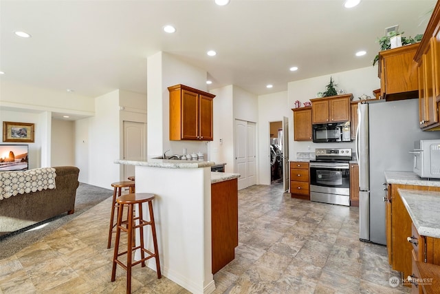 kitchen featuring stainless steel appliances, a breakfast bar area, and light stone countertops