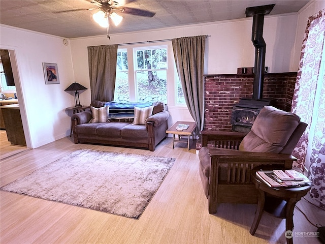 sitting room featuring light hardwood / wood-style floors, ceiling fan, a wood stove, and crown molding