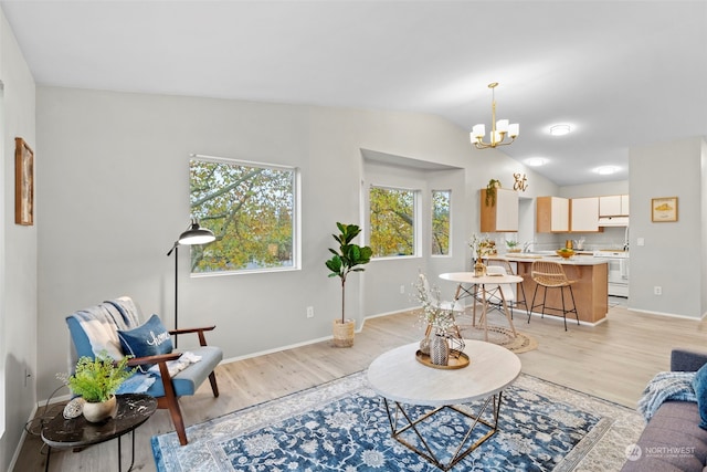 living room with light wood-type flooring, vaulted ceiling, and an inviting chandelier