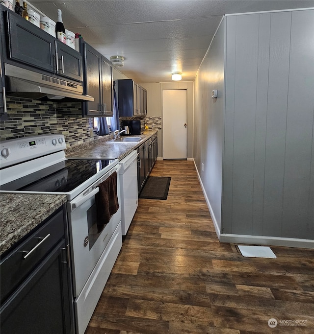 kitchen featuring sink, dark hardwood / wood-style floors, dark stone countertops, white appliances, and decorative backsplash