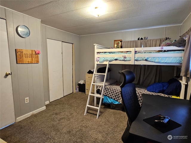 carpeted bedroom featuring wood walls and a closet