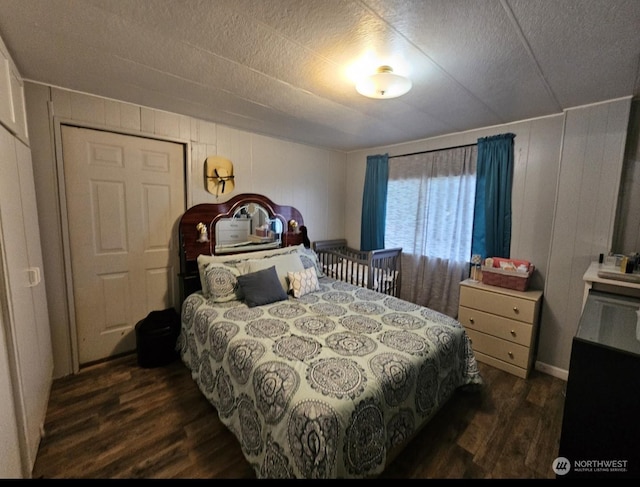 bedroom with a textured ceiling, dark hardwood / wood-style flooring, and wood walls