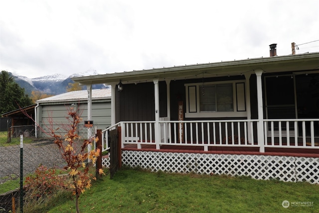 back of property with a lawn, a mountain view, and covered porch