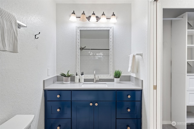 bathroom featuring toilet, a shower, and vanity