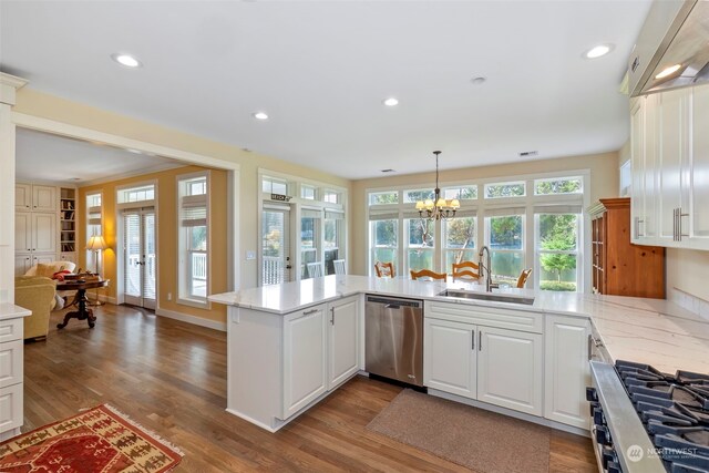 kitchen with white cabinetry, sink, stainless steel appliances, kitchen peninsula, and hardwood / wood-style flooring