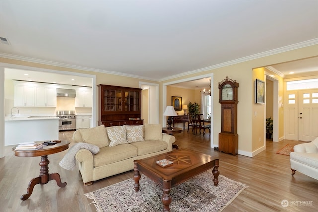 living room with light wood-type flooring, an inviting chandelier, and ornamental molding