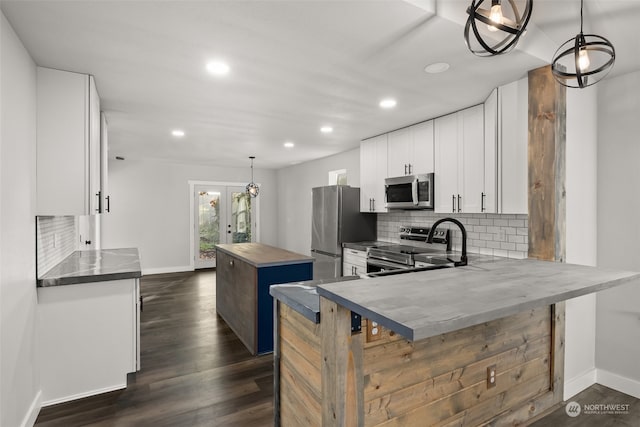 kitchen featuring stainless steel appliances, dark hardwood / wood-style floors, a center island, white cabinets, and pendant lighting