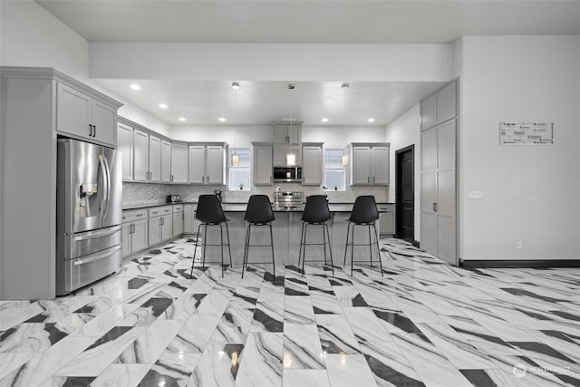 205 Clayton Pl, Mattawa, WA 99349 - kitchen featuring stainless steel appliances, gray cabinetry, a kitchen breakfast bar, tasteful backsplash, and a center island