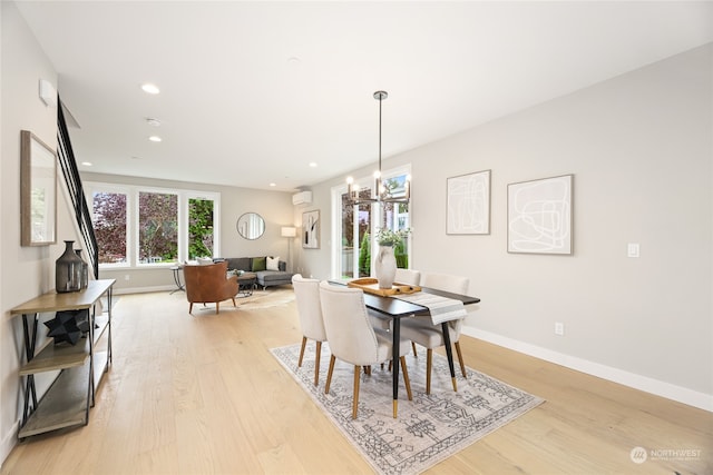 dining space with a wall mounted AC, light hardwood / wood-style flooring, and an inviting chandelier