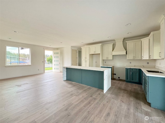 kitchen featuring a center island, white cabinets, custom range hood, and light wood-type flooring