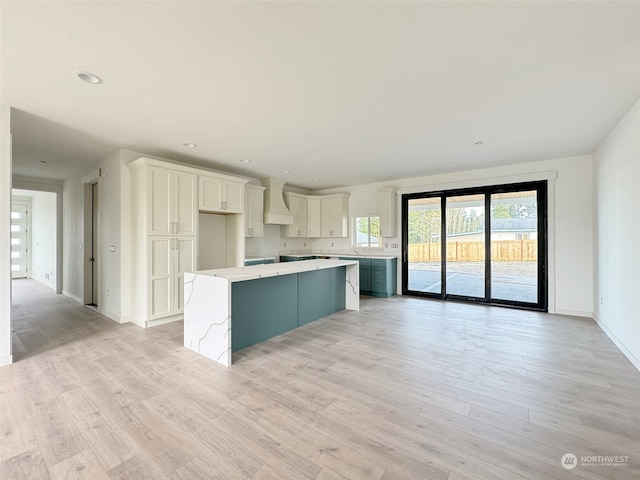 kitchen featuring light hardwood / wood-style floors, a kitchen island, white cabinetry, and premium range hood