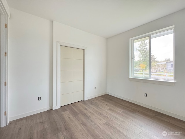 unfurnished bedroom with a closet and light hardwood / wood-style floors