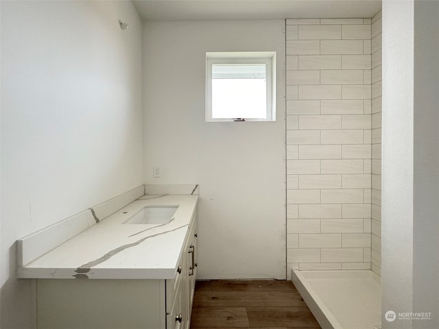 bathroom with hardwood / wood-style flooring, vanity, and a shower