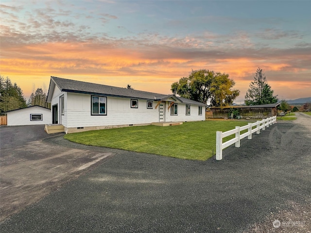 ranch-style home featuring a lawn and an outbuilding