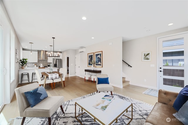 living room featuring light wood-type flooring, a wall unit AC, and a chandelier