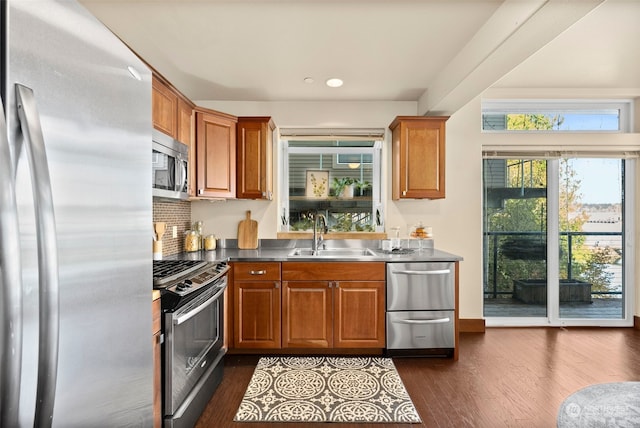 kitchen featuring dark wood-type flooring, decorative backsplash, appliances with stainless steel finishes, and sink