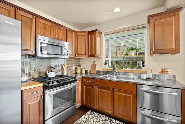 kitchen featuring dark wood-type flooring, decorative backsplash, appliances with stainless steel finishes, and sink