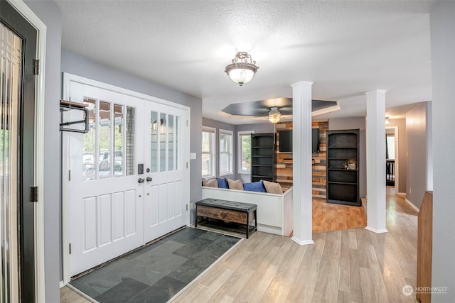 foyer entrance with decorative columns, a textured ceiling, ceiling fan, and light hardwood / wood-style flooring