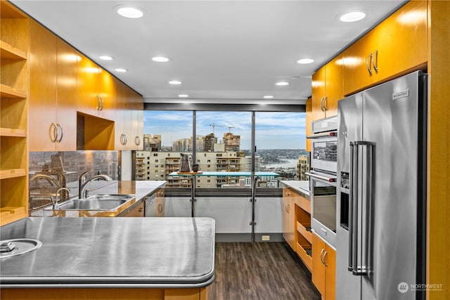 kitchen with sink, appliances with stainless steel finishes, tasteful backsplash, stainless steel counters, and dark wood-type flooring