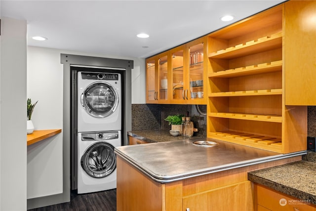 washroom featuring dark hardwood / wood-style flooring and stacked washer / dryer