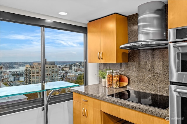 kitchen featuring black electric cooktop, wall chimney range hood, and tasteful backsplash