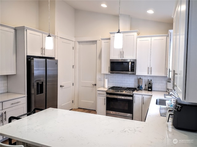 kitchen with stainless steel appliances, white cabinets, decorative light fixtures, and decorative backsplash