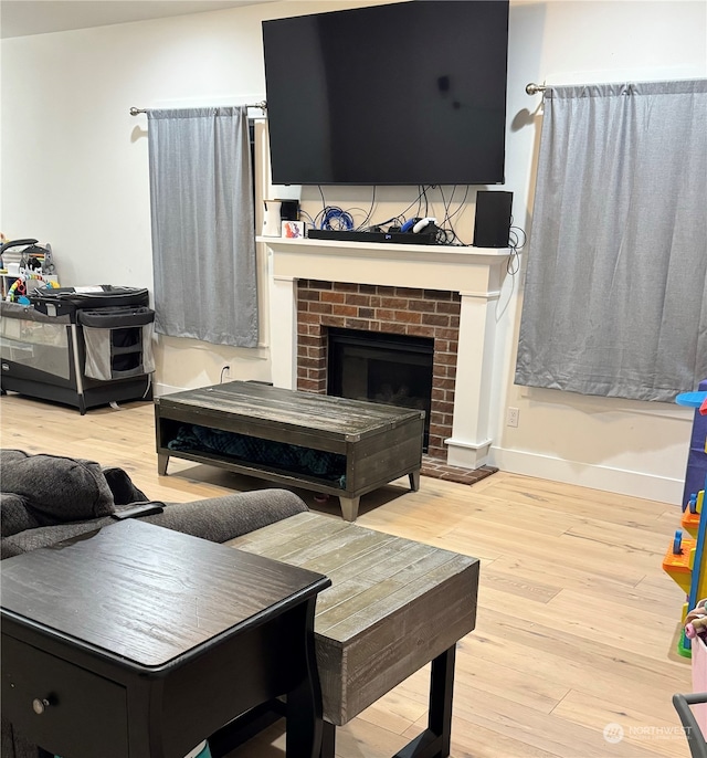 living room with a brick fireplace and light hardwood / wood-style flooring