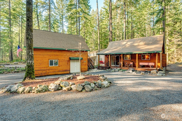 log cabin featuring a porch and a garage