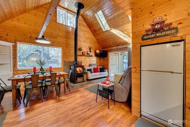 dining area with a healthy amount of sunlight, wooden walls, and high vaulted ceiling