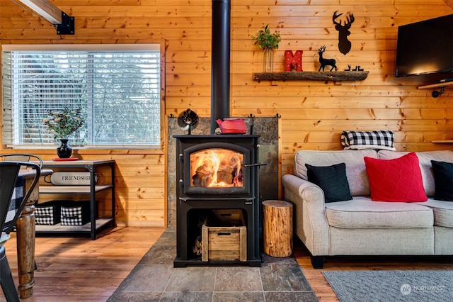 sitting room with a wood stove, wood-type flooring, and wooden walls