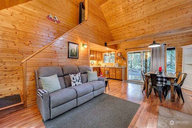 living room featuring light wood-type flooring, wooden walls, and a high ceiling