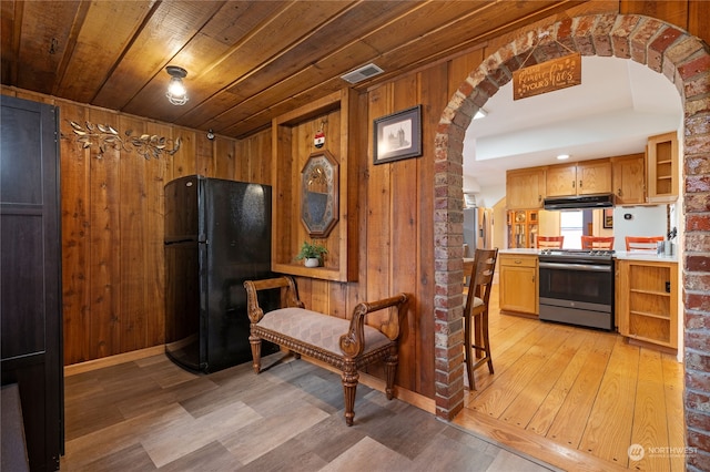 kitchen featuring arched walkways, open shelves, appliances with stainless steel finishes, wooden walls, and wooden ceiling