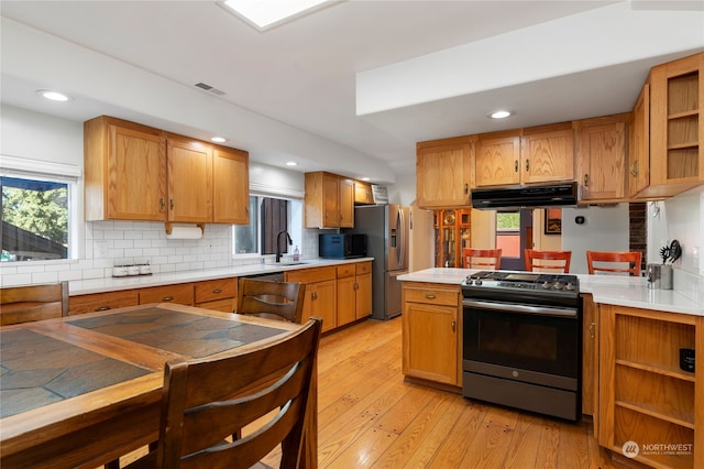 kitchen with open shelves, stainless steel appliances, light wood-style flooring, a sink, and under cabinet range hood