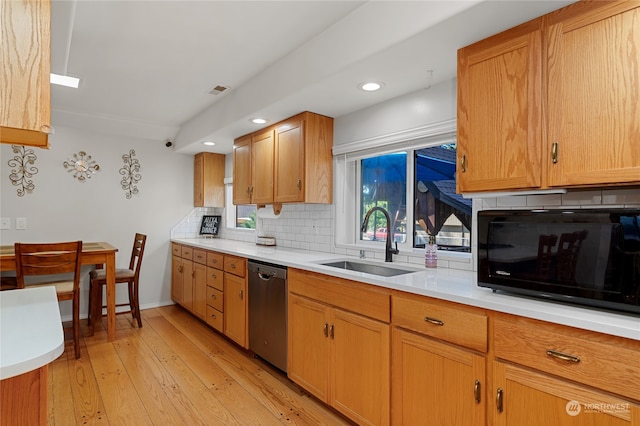 kitchen featuring black microwave, light wood-style flooring, a sink, light countertops, and dishwasher