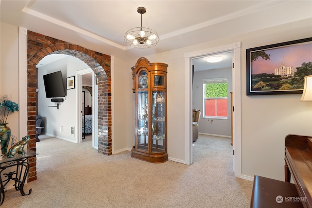 corridor with carpet floors, baseboards, arched walkways, and a raised ceiling