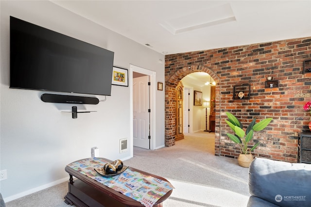 carpeted living area featuring arched walkways, baseboards, visible vents, and brick wall