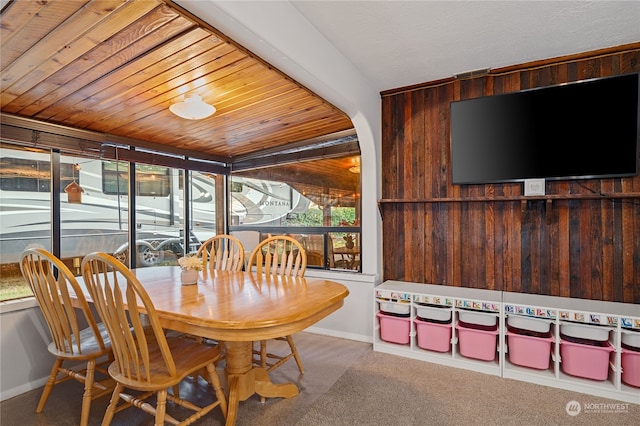 carpeted dining area with wooden ceiling and baseboards