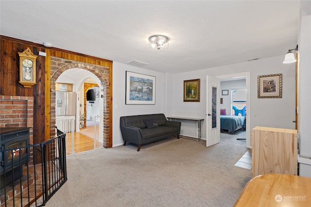 sitting room with arched walkways, wood walls, carpet, and visible vents