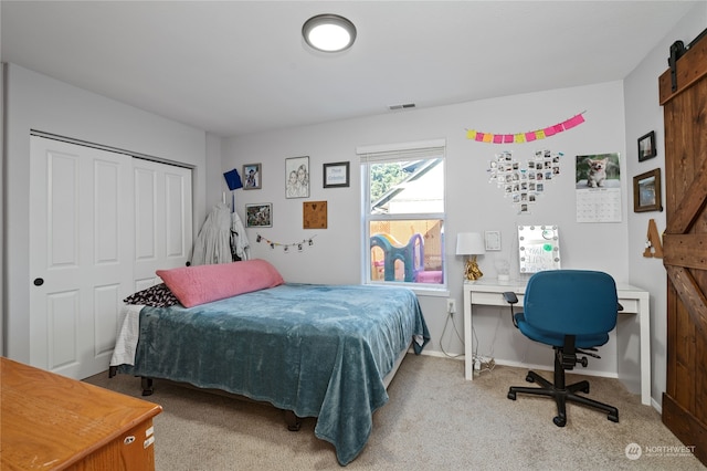 bedroom featuring carpet floors, a closet, visible vents, a barn door, and baseboards