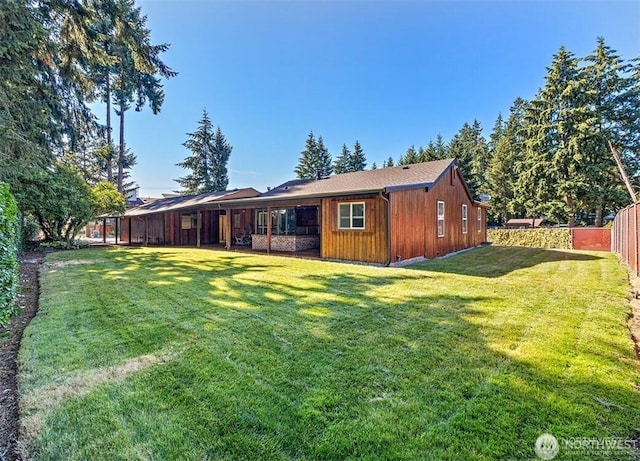 back of house featuring fence and a lawn