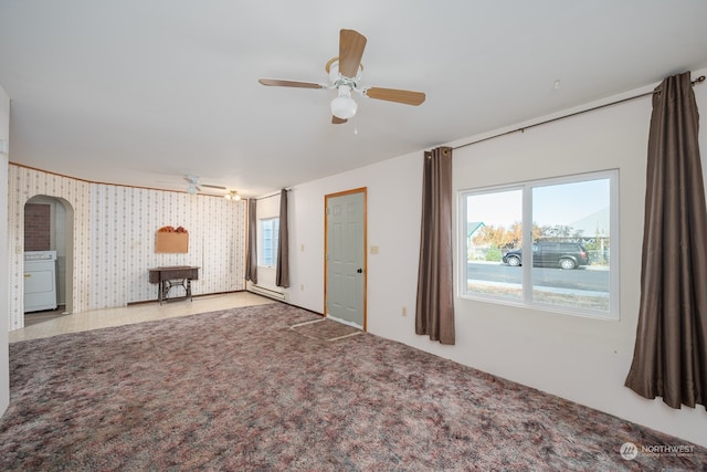 carpeted empty room featuring a baseboard radiator, ceiling fan, and washer / dryer