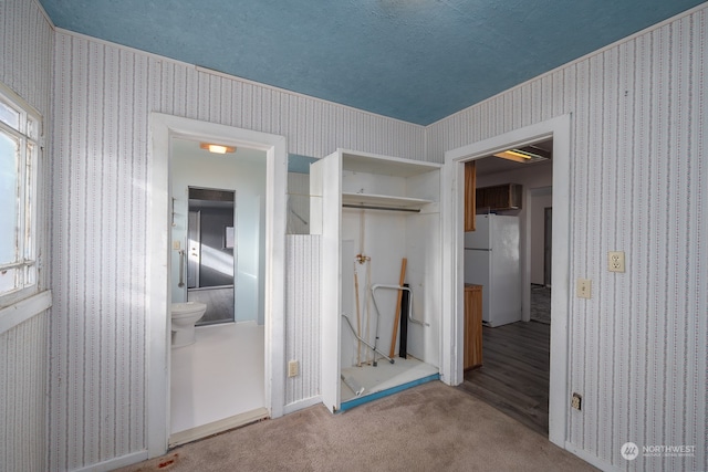 unfurnished bedroom with carpet flooring, a textured ceiling, white refrigerator, and a closet