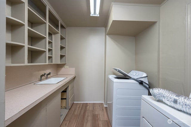 clothes washing area featuring washing machine and dryer, light hardwood / wood-style floors, and sink