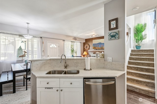 kitchen featuring white cabinetry, stainless steel dishwasher, sink, and light stone counters