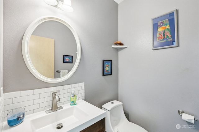 bathroom featuring toilet, vanity, and tasteful backsplash