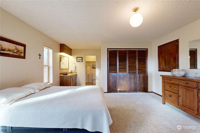 carpeted bedroom with connected bathroom, a closet, and a textured ceiling