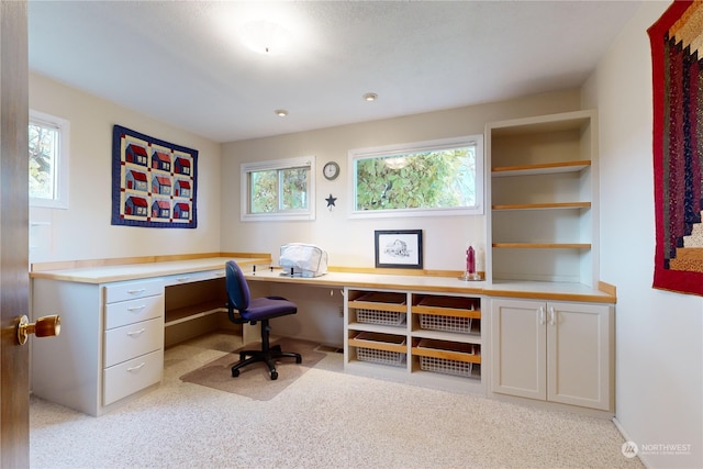 home office with built in desk and light colored carpet