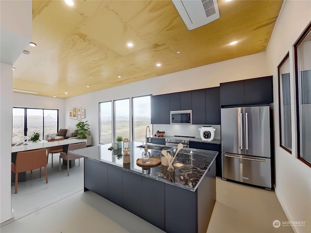 kitchen with a healthy amount of sunlight, sink, an island with sink, and appliances with stainless steel finishes