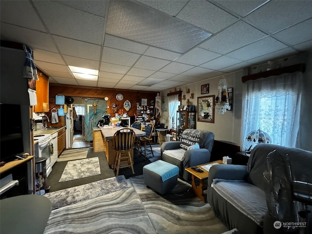 living room with wood walls and a drop ceiling