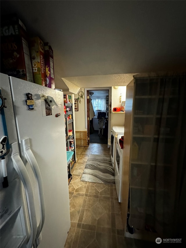 interior space featuring washing machine and dryer and white fridge with ice dispenser